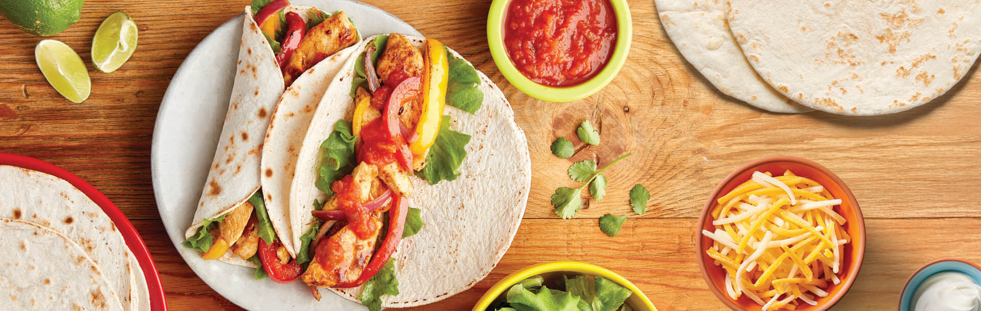 wrap messicani serviti con salsa e formaggio grattugiato su un tavolo di legno